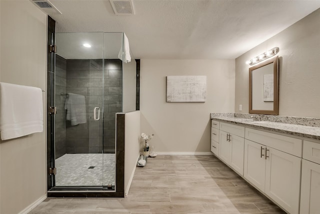 4053 Winfield Ave, Fort Worth, TX 76109 - bathroom with vanity, a shower stall, a textured ceiling, and wood finished floors