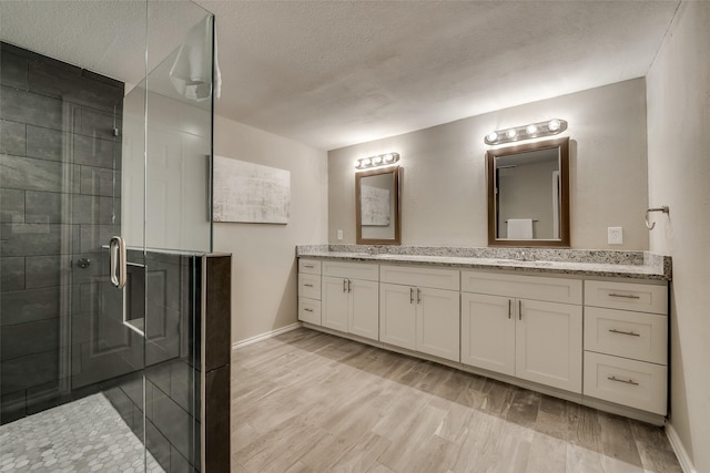 4053 Winfield Ave, Fort Worth, TX 76109 - bathroom with double vanity, a stall shower, a textured ceiling, and wood finished floors