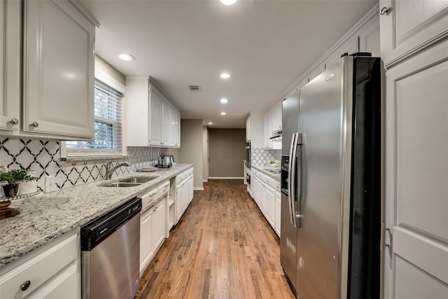 4053 Winfield Ave, Fort Worth, TX 76109 - kitchen featuring stainless steel appliances, light wood-type flooring, recessed lighting, tasteful backsplash, and white cabinetry