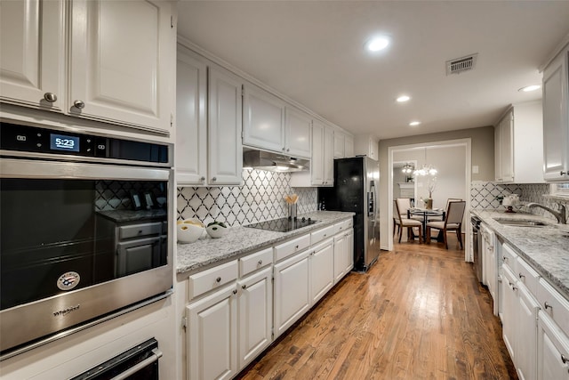 4053 Winfield Ave, Fort Worth, TX 76109 - kitchen with stainless steel appliances, white cabinetry, under cabinet range hood, decorative backsplash, and recessed lighting