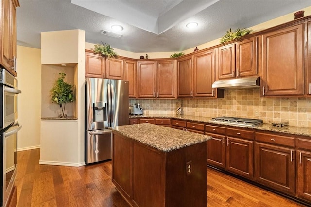 6321 Cobblestone Ln, Arlington, TX 76001 - kitchen with stainless steel appliances, under cabinet range hood, light stone counters, and decorative backsplash