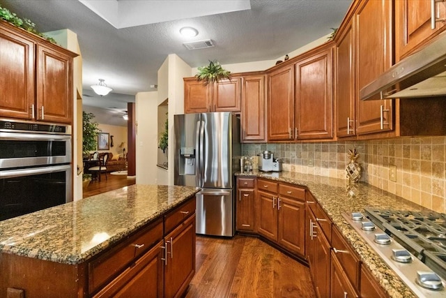 6321 Cobblestone Ln, Arlington, TX 76001 - kitchen featuring appliances with stainless steel finishes, under cabinet range hood, dark wood finished floors, and stone counters