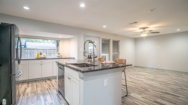 1031 Oak Hurst Dr, Grapevine, TX 76051 - kitchen with appliances with stainless steel finishes, light wood-style flooring, a ceiling fan, a center island with sink, and a kitchen breakfast bar