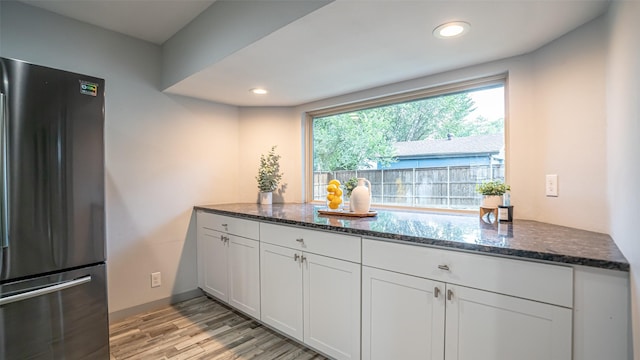 1031 Oak Hurst Dr, Grapevine, TX 76051 - kitchen with freestanding refrigerator, light wood-style flooring, dark stone counters, white cabinets, and recessed lighting