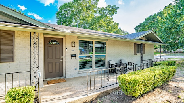 1031 Oak Hurst Dr, Grapevine, TX 76051 - view of exterior entry featuring brick siding, roof with shingles, and covered porch
