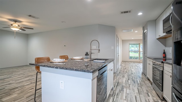 1031 Oak Hurst Dr, Grapevine, TX 76051 - kitchen with a breakfast bar, appliances with stainless steel finishes, light wood-style flooring, a kitchen island with sink, and recessed lighting