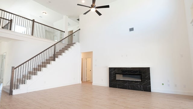 1032 Meadowlark, Forney, TX 75126 - unfurnished living room with a towering ceiling, wood finished floors, ceiling fan, stairway, and a high end fireplace