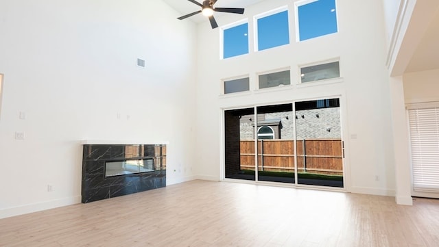 1032 Meadowlark, Forney, TX 75126 - unfurnished living room with ceiling fan, a high end fireplace, a towering ceiling, and wood finished floors