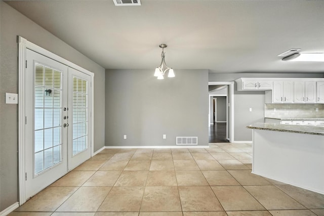 1208 Homestead St, Flower Mound, TX 75028 - kitchen featuring french doors, light stone counters, light tile patterned floors, white cabinets, and decorative light fixtures