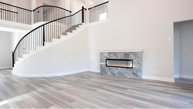 850 Blue Heron Dr, Forney, TX 75126 - unfurnished living room with a towering ceiling, wood finished floors, stairs, and a premium fireplace