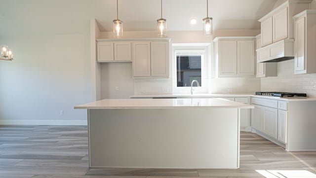 850 Blue Heron Dr, Forney, TX 75126 - kitchen featuring a kitchen island, backsplash, light wood finished floors, ventilation hood, and light countertops