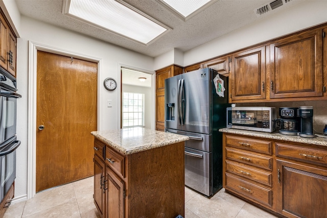 4645 Pecan Place Dr, Mckinney, TX 75071 - kitchen with stainless steel appliances, a center island, light tile patterned floors, light stone counters, and a textured ceiling