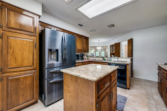 4645 Pecan Place Dr, Mckinney, TX 75071 - kitchen featuring stainless steel fridge, dishwasher, a kitchen island, brown cabinets, and light stone countertops