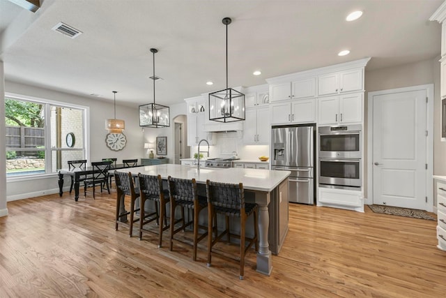 5705 Heron Dr E, Colleyville, TX 76034 - kitchen with stainless steel appliances, light countertops, light wood finished floors, white cabinets, and recessed lighting