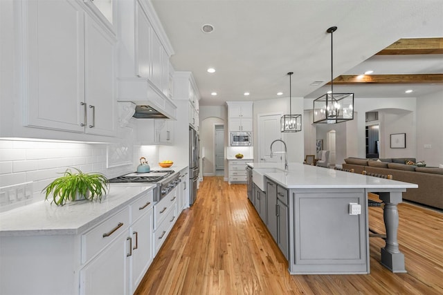 5705 Heron Dr E, Colleyville, TX 76034 - kitchen featuring appliances with stainless steel finishes, arched walkways, light wood-style floors, recessed lighting, and white cabinetry