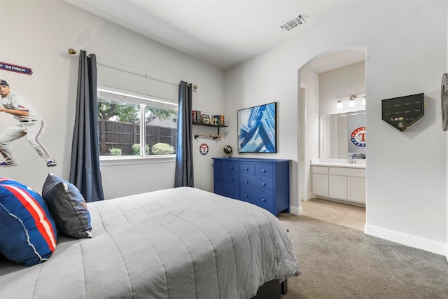 5705 Heron Dr E, Colleyville, TX 76034 - bedroom featuring arched walkways, light colored carpet, ensuite bathroom, and light tile patterned flooring