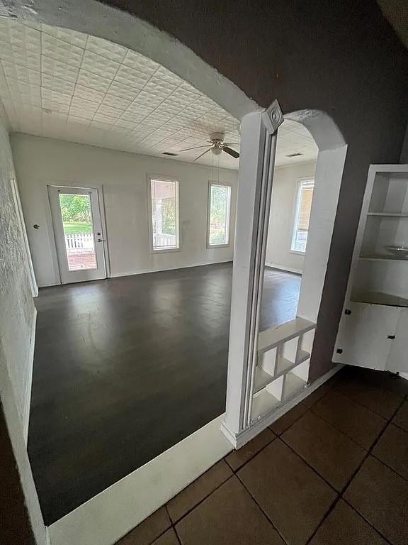 705 W Green St, Palestine, TX 75801 - tiled empty room with arched walkways, plenty of natural light, and ceiling fan
