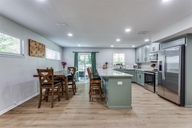 4105 Micki Lynn Ave, Fort Worth, TX 76107 - kitchen featuring stainless steel appliances, a peninsula, light countertops, light wood finished floors, and plenty of natural light