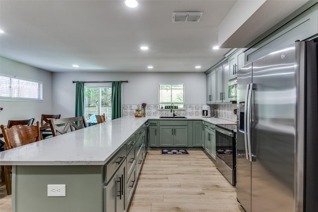 4105 Micki Lynn Ave, Fort Worth, TX 76107 - kitchen with stainless steel appliances, a peninsula, recessed lighting, light stone counters, and light wood-type flooring