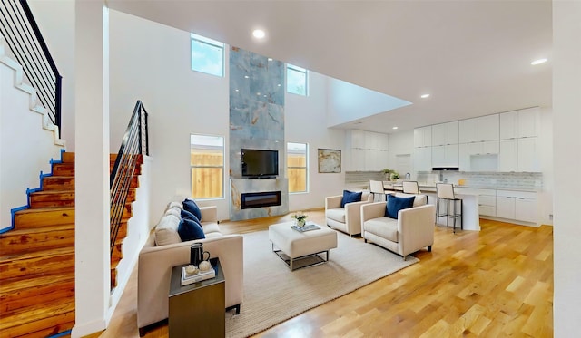 3418 Borger St, Dallas, TX 75212 - living room featuring a towering ceiling, stairway, recessed lighting, light wood-style flooring, and a premium fireplace