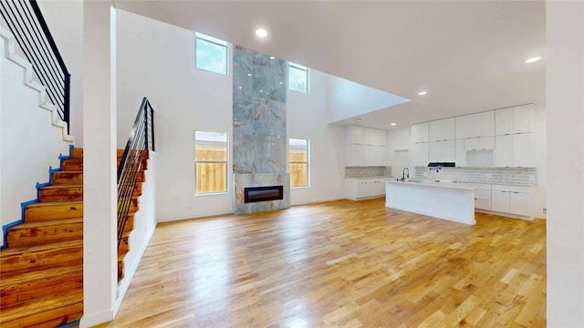 3418 Borger St, Dallas, TX 75212 - unfurnished living room featuring stairway, light wood-style flooring, a high ceiling, recessed lighting, and a fireplace