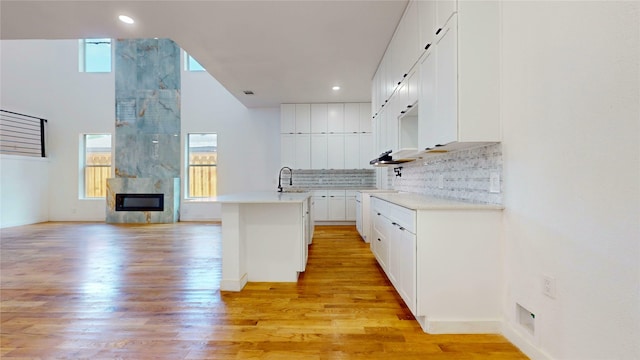 3418 Borger St, Dallas, TX 75212 - kitchen with tasteful backsplash, light wood finished floors, an island with sink, white cabinetry, and recessed lighting