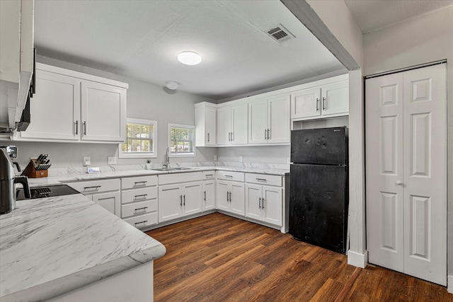 25 W Parnell St, Denison, TX 75020 - kitchen featuring freestanding refrigerator, light stone counters, white cabinets, and dark wood-type flooring