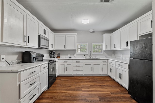 25 W Parnell St, Denison, TX 75020 - kitchen featuring black appliances, white cabinets, dark wood-type flooring, and light stone countertops