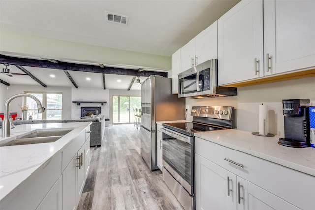 738 Campground Rd, Sherman, TX 75090 - kitchen with stainless steel appliances, light wood-type flooring, white cabinets, beam ceiling, and light stone counters
