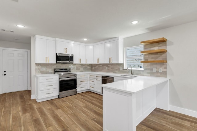 2917 NW Loraine St, Fort Worth, TX 76106 - kitchen with appliances with stainless steel finishes, light wood-style flooring, a peninsula, light countertops, and backsplash