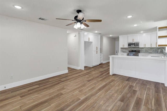 2917 NW Loraine St, Fort Worth, TX 76106 - kitchen featuring stainless steel appliances, open shelves, light wood-type flooring, a peninsula, and backsplash