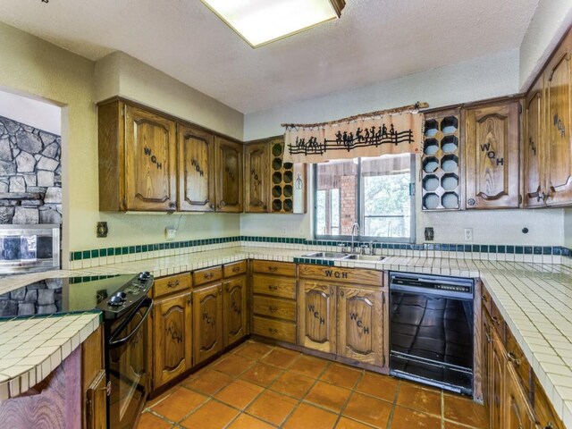 5403 Oakridge Rd, Joshua, TX 76058 - kitchen with black appliances, tile countertops, dark tile patterned flooring, and brown cabinets