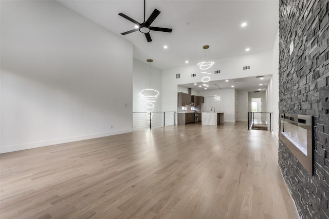 1521 N Haskell Ave, Dallas, TX 75204 - unfurnished living room featuring a high ceiling, a ceiling fan, a fireplace, recessed lighting, and light wood-style floors