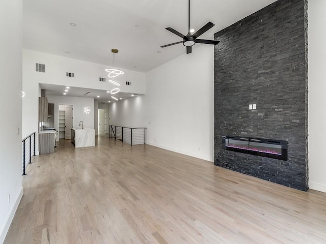 1521 N Haskell Ave, Dallas, TX 75204 - unfurnished living room with light wood finished floors, ceiling fan, a high ceiling, and a fireplace