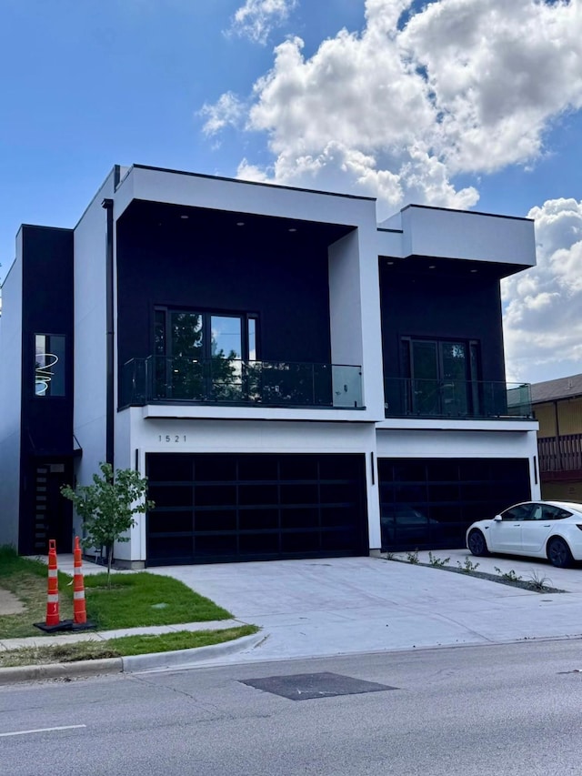 1521 N Haskell Ave, Dallas, TX 75204 - modern home featuring stucco siding, an attached garage, a balcony, and driveway