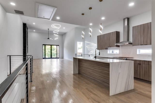 1521 N Haskell Ave, Dallas, TX 75204 - kitchen with modern cabinets, wall chimney exhaust hood, a center island with sink, light wood-type flooring, and light countertops