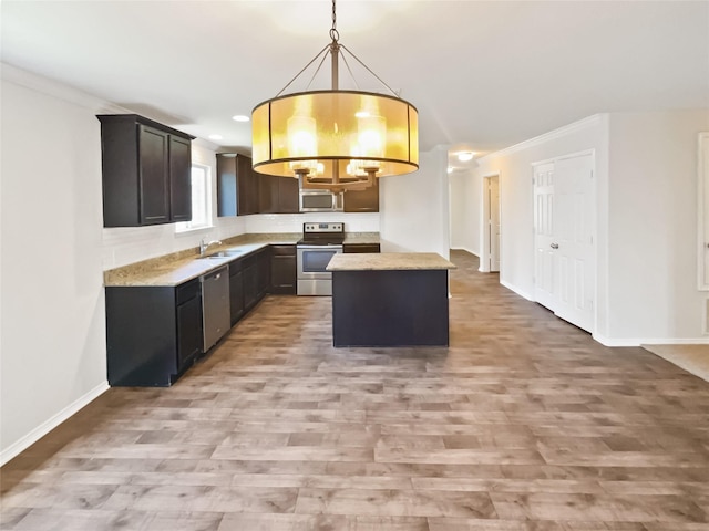1409 Rivers Creek Ln, Little Elm, TX 75068 - kitchen with appliances with stainless steel finishes, light wood-style floors, ornamental molding, a center island, and pendant lighting
