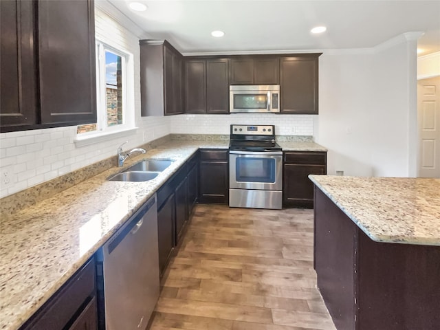 1409 Rivers Creek Ln, Little Elm, TX 75068 - kitchen with appliances with stainless steel finishes, crown molding, light wood finished floors, dark brown cabinets, and tasteful backsplash
