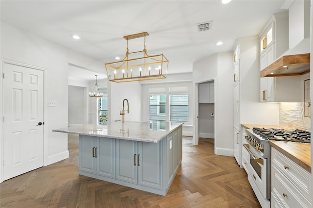 2705 Jackson Dr, Melissa, TX 75454 - kitchen with wall chimney exhaust hood, range with gas cooktop, a chandelier, recessed lighting, and white cabinets