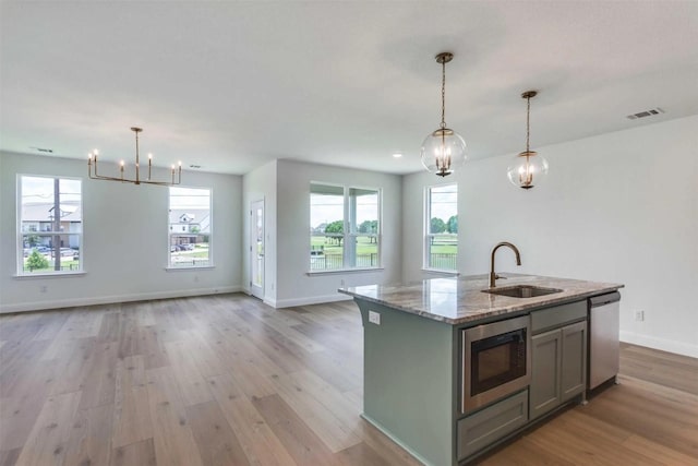 304 Ridge Dr, Justin, TX 76247 - kitchen with appliances with stainless steel finishes, gray cabinetry, open floor plan, a chandelier, and light wood-style flooring