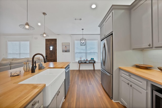 940 E 5th St, Springtown, TX 76082 - kitchen featuring wooden counters, stainless steel appliances, dark wood-type flooring, gray cabinetry, and decorative backsplash