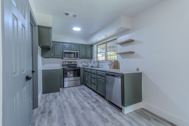 10029 Grove Oaks Blvd, Dallas, TX 75217 - kitchen with stainless steel appliances, light wood-type flooring, open shelves, light countertops, and gray cabinets