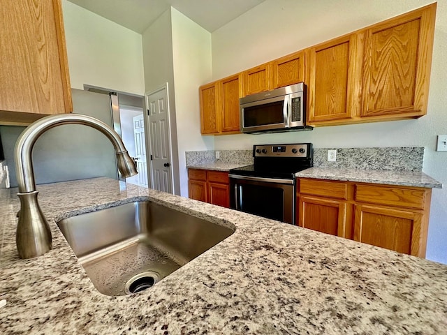 917 Calder St, Howe, TX 75459 - kitchen featuring appliances with stainless steel finishes, brown cabinetry, and light stone counters