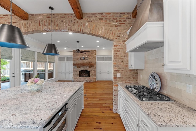1030 Winterberry Ln, Shreveport, LA 71106 - kitchen with stainless steel gas cooktop, light wood-type flooring, premium range hood, ceiling fan, and white cabinets