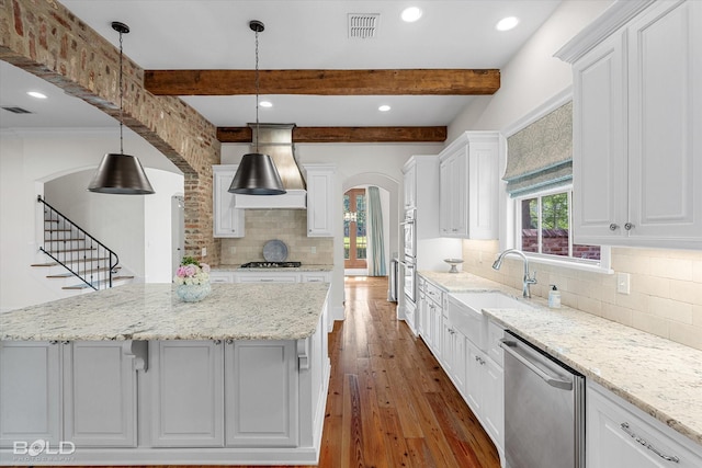 1030 Winterberry Ln, Shreveport, LA 71106 - kitchen with arched walkways, appliances with stainless steel finishes, hardwood / wood-style floors, white cabinetry, and backsplash