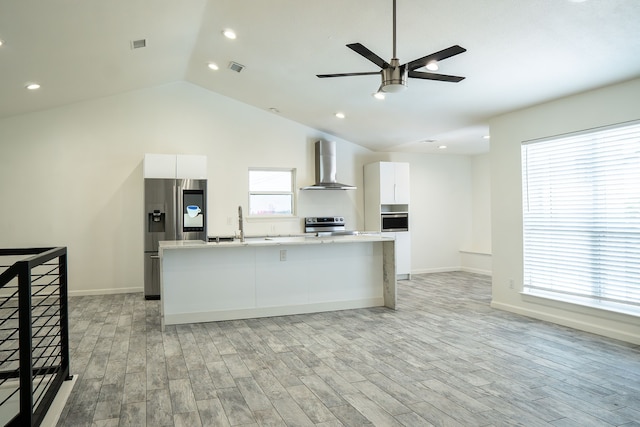 624 Mission Hills Dr, Arlington, TX 76018 - kitchen with wall chimney range hood, appliances with stainless steel finishes, light wood-style floors, a center island with sink, and vaulted ceiling