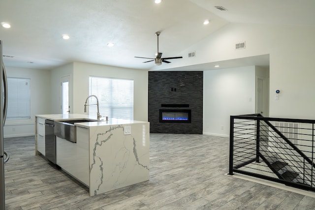 624 Mission Hills Dr, Arlington, TX 76018 - kitchen featuring a ceiling fan, light wood finished floors, an island with sink, dishwasher, and light stone counters