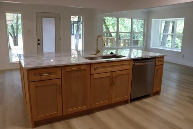 129 Oak Trl, Burleson, TX 76028 - kitchen featuring stainless steel dishwasher, light wood-type flooring, light stone countertops, and an island with sink