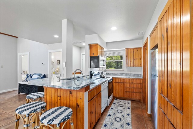 3125 County Road 264, Breckenridge, TX 76424 - kitchen with appliances with stainless steel finishes, a peninsula, light tile patterned floors, and brown cabinetry