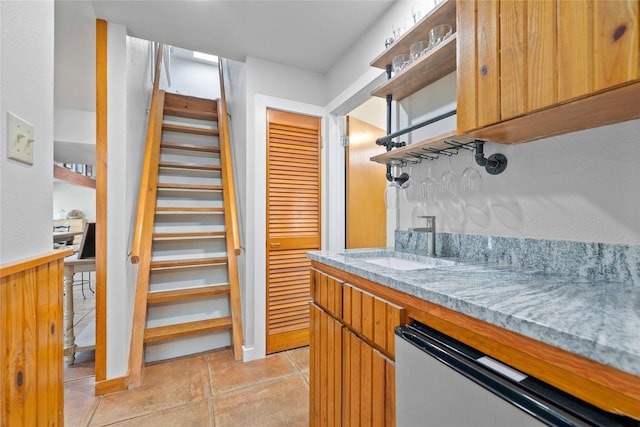 3125 County Road 264, Breckenridge, TX 76424 - kitchen with open shelves, dishwashing machine, light stone counters, and brown cabinetry